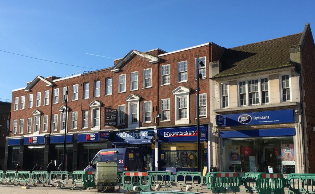 brick parade of shops with two stories of pedimented sash windows.