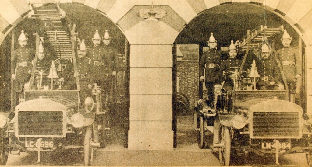 sepia photo of firemen, with fine helmets, under station arches