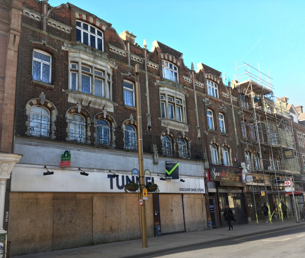 ornate turn of the century building with juliette balconies and buddliah growing out of it