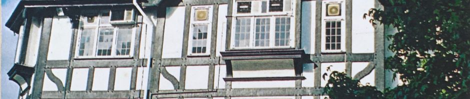 Corner of building with jutting windows and black beams dividing it into pleasing blocks