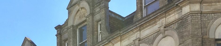 nice arched dormer window with date in yellow stone and brick